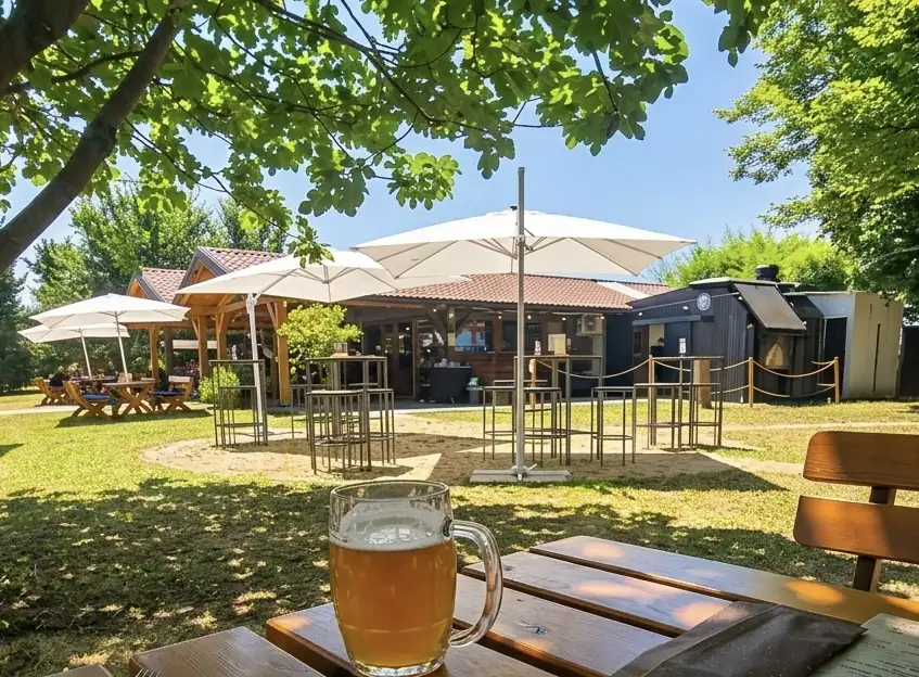 Dehors coperto con ombrelloni bianchi e boccale di birra in primo piano
